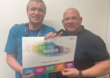 Two men standing side by side holding a colourful poster explaining Ingeus